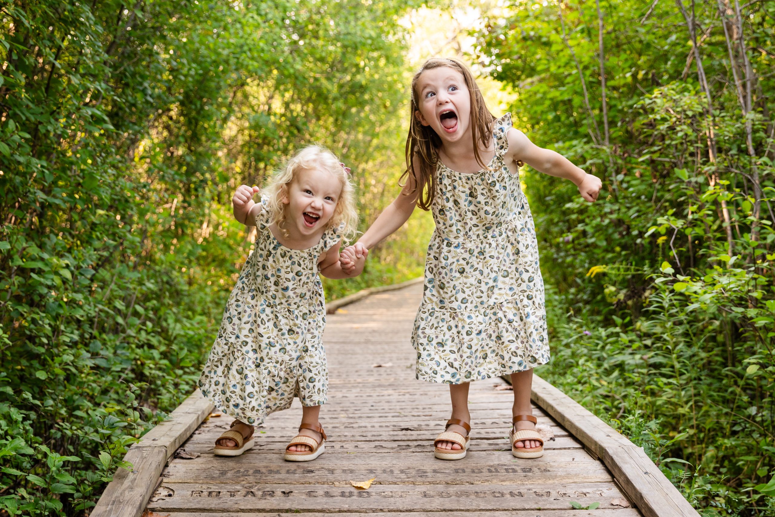 fun sibling photography london ontario with two girls screaming for a candid photo at westminster pond