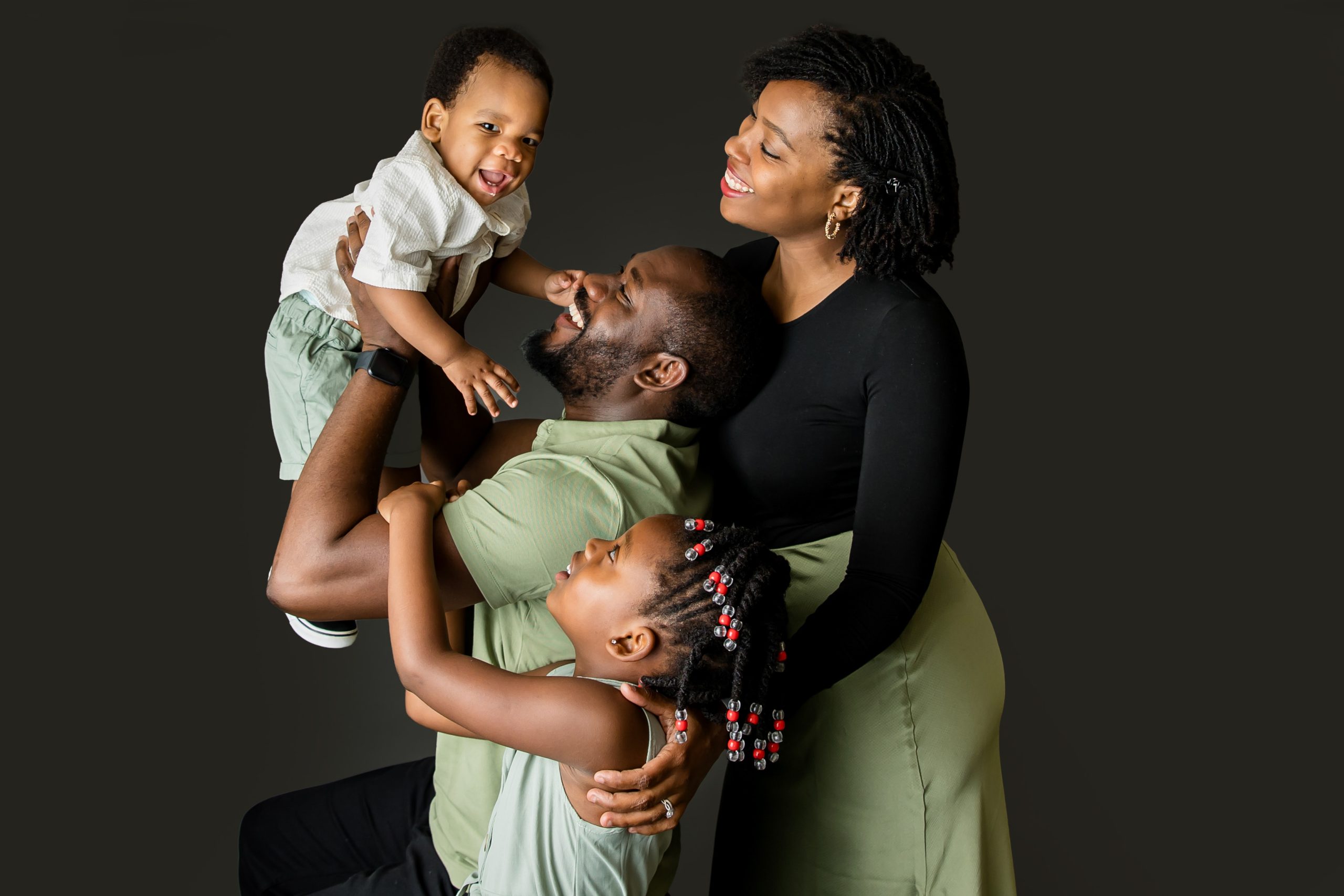 studio photography london ontatio family smiles up at baby being held up by dad.