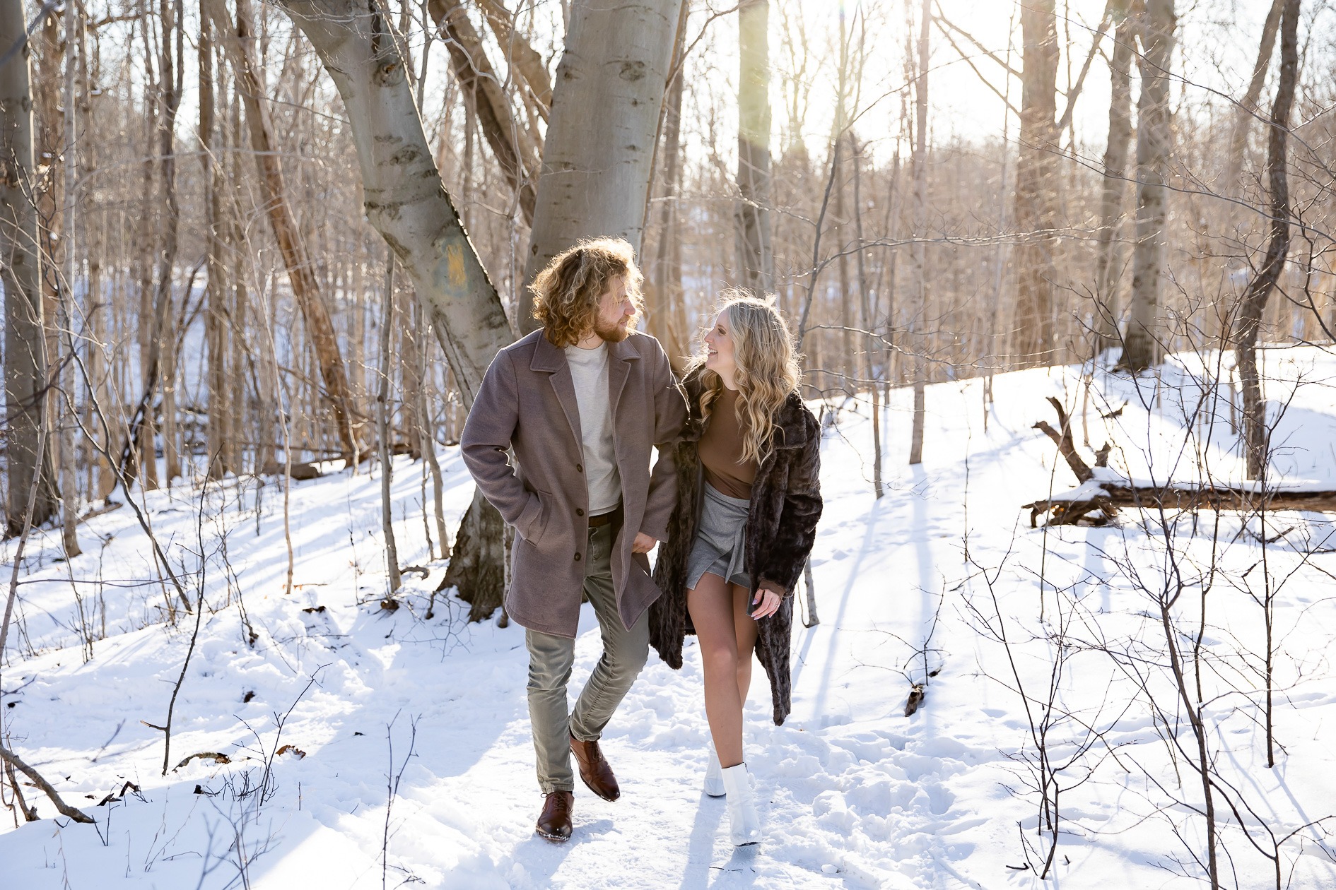 winter Engagement Photography London Ontario couple walk towards camera with snow on the ground at medway forest