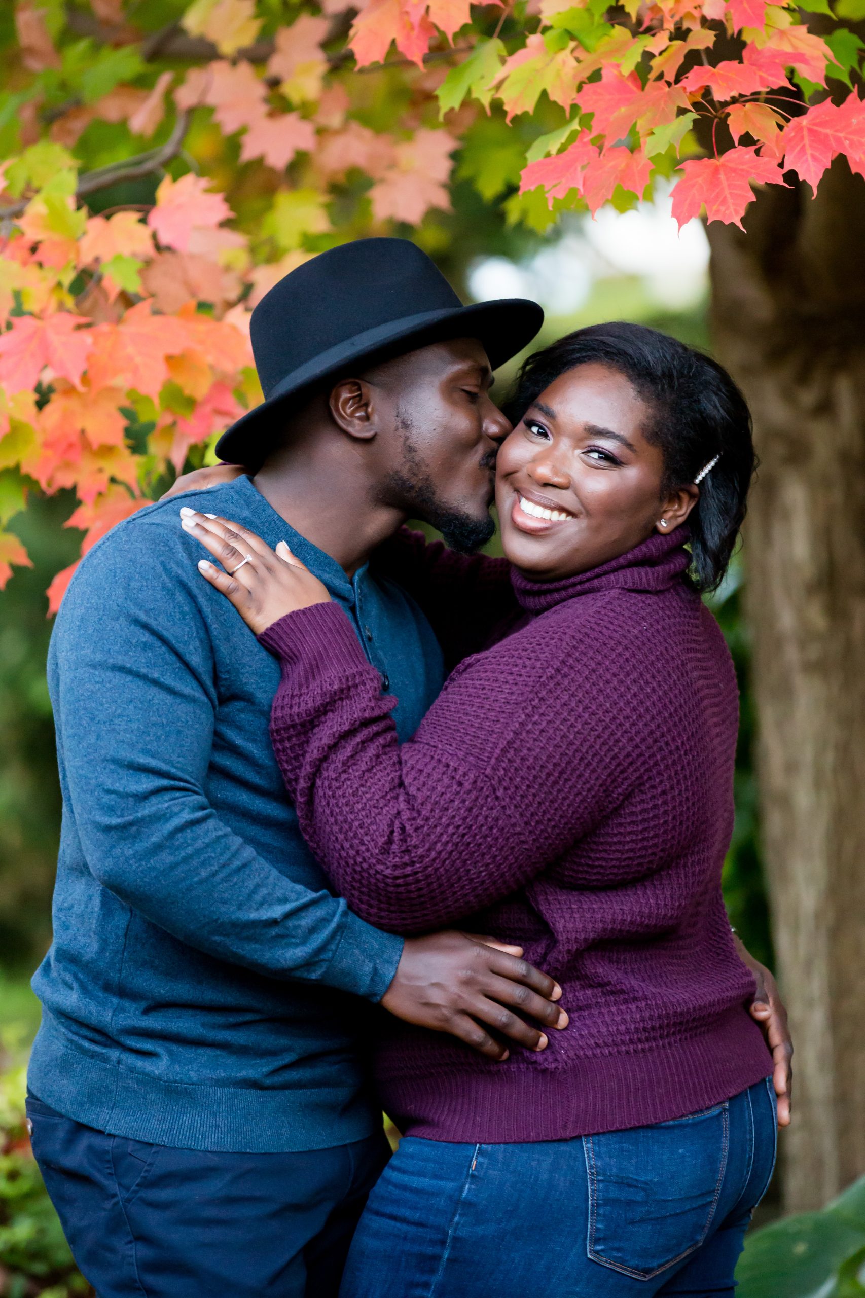 Engagement Photography London Ontario couple kiss in front of fall leaves at ivey park