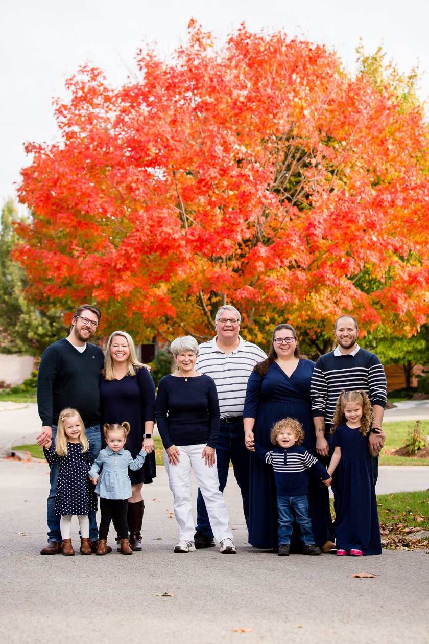 family photography london ontario wearing navy and white smiling at camera with vibrant fall tree in background