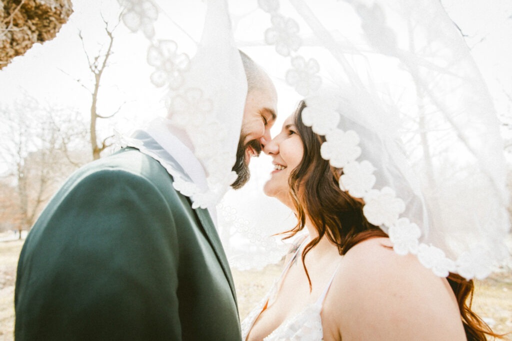 couple smile at each other underneath veil wedding photography london ontario