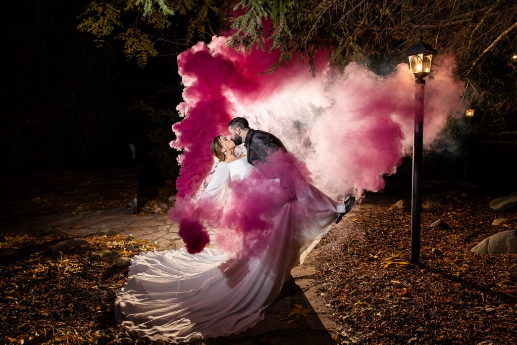 couple dip and kiss surrounded by a pink smoke bomb london ontario wedding photography